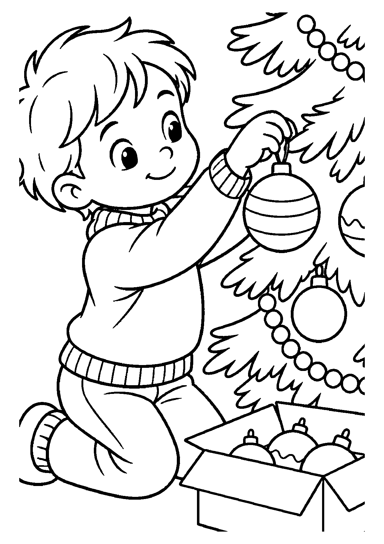 A smiling boy kneeling by a Christmas tree hangs a striped bauble on a branch, next to an open box of more ornaments