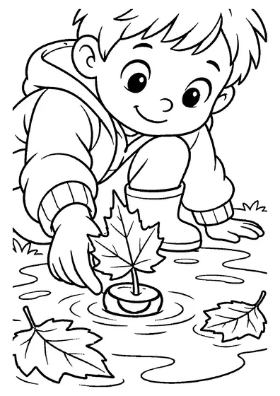A smiling boy in a hooded jacket and rubber boots sets a chestnut boat with a maple leaf sail on an autumn puddle
